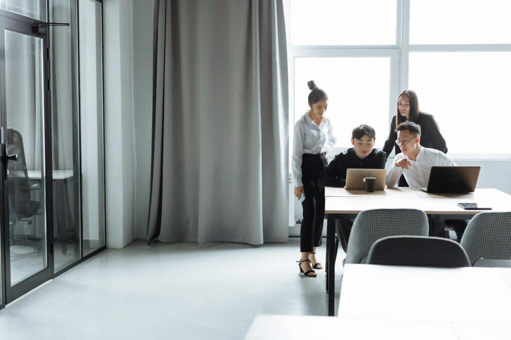 A diverse office team collaborating on laptops during daylight hours.