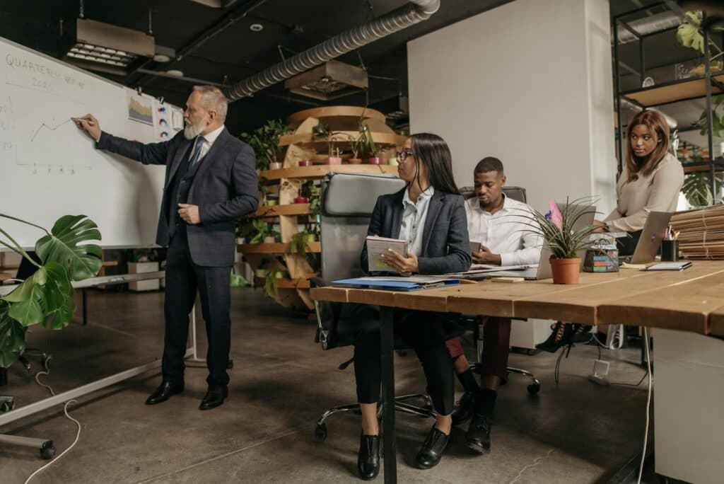 Business professionals engage in a team meeting with a whiteboard presentation in a modern office.