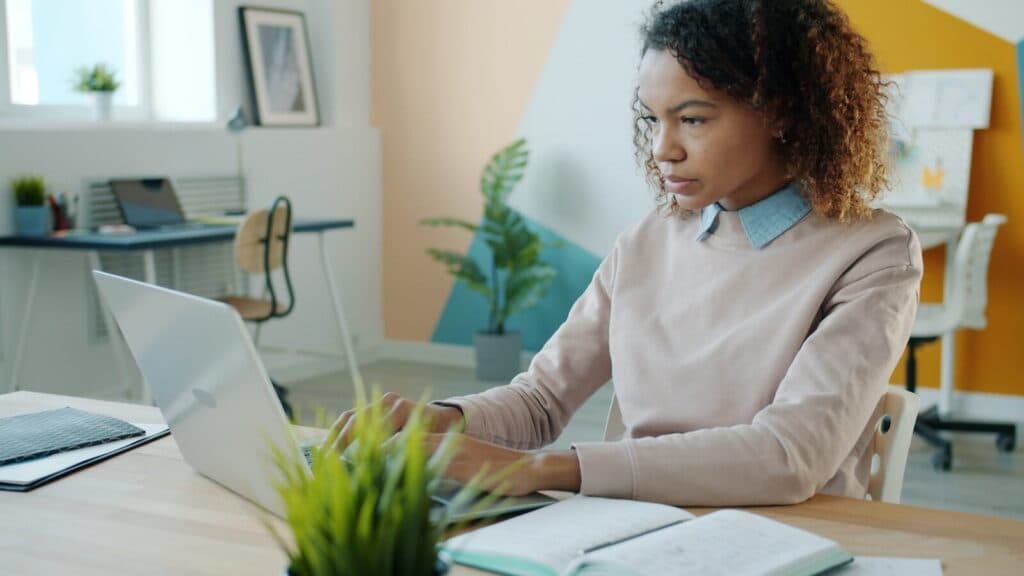 A young woman working on a laptop in an office.